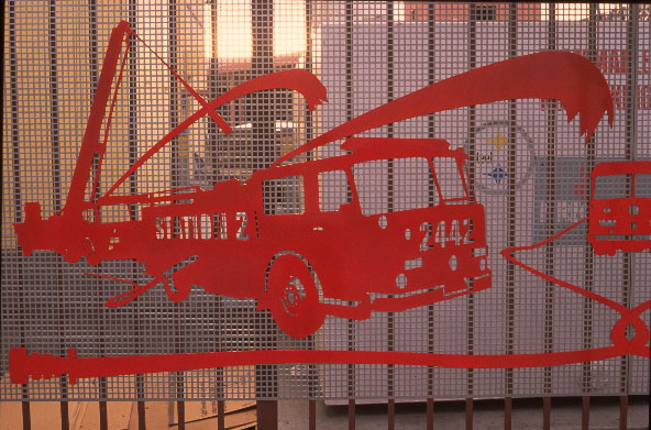 red fire engine cutout attached to a fence grating